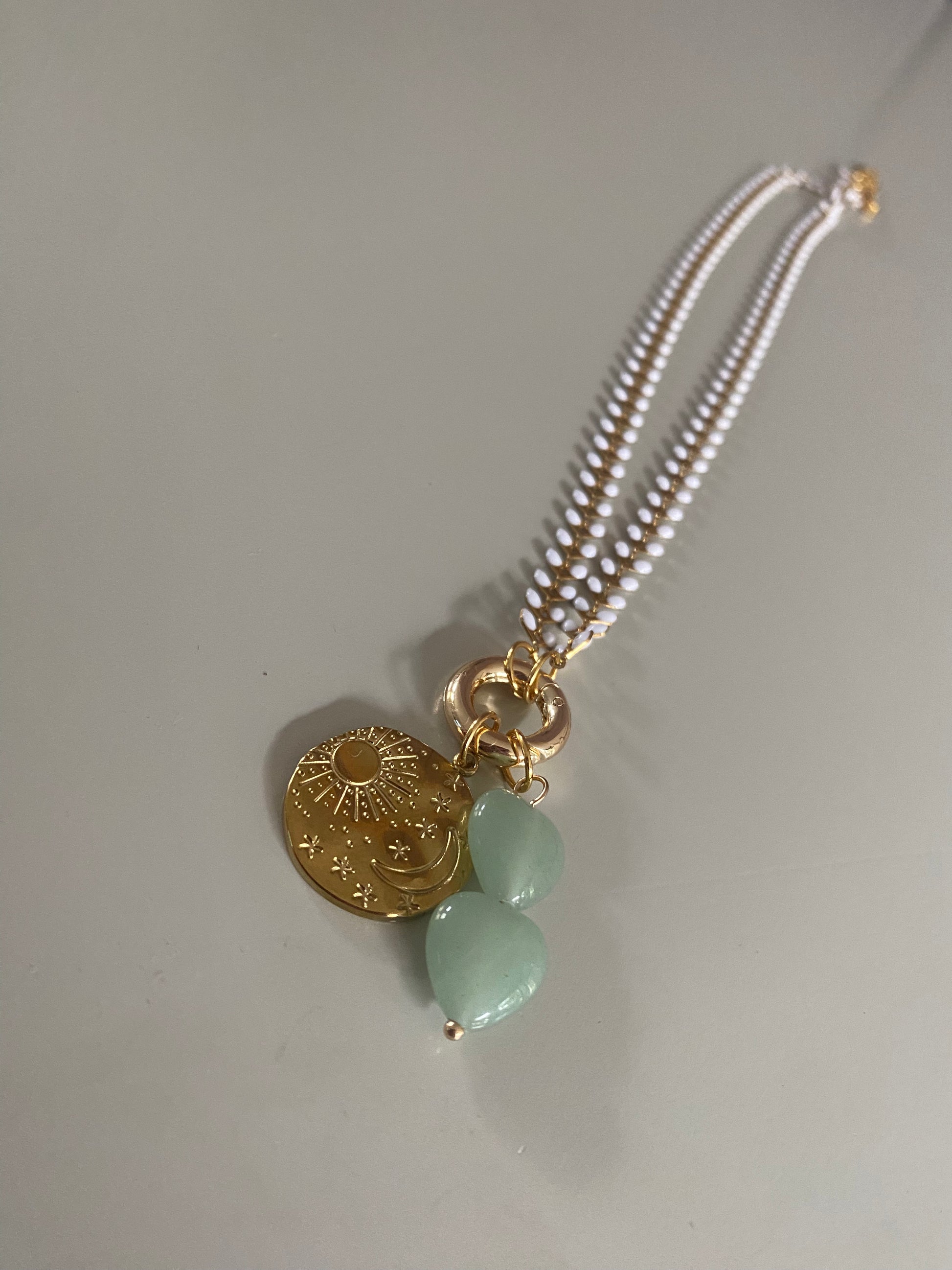 Emaille witte blaadjes ketting met daaraan een connector en 18K vergulde zon maar sterren bedel en 2 jadegroene natuurstenen hartjes aan een connector.