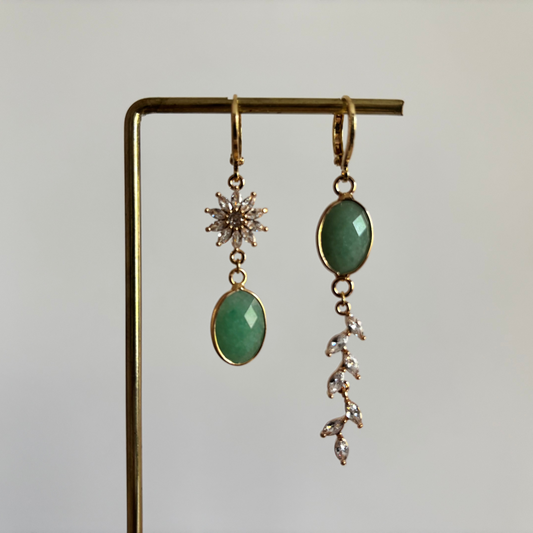 Asymmetrische set 14k vergulde oorringetjes Marietje met aan de ene kant een mintgroene natuursteen onder een zirkonia bloem en aan de andere kant een streng van zirkonia blaadjes.
