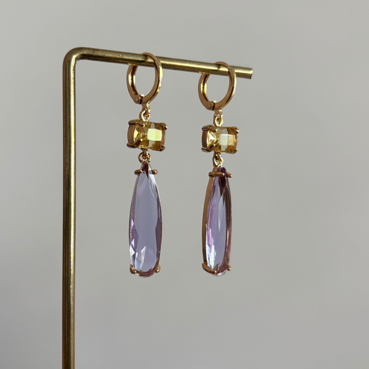 14k vergulde oorbellen model Maya met een vierkante gele kristallen steen en een hangende, lila druppelvormige kristalsteen.