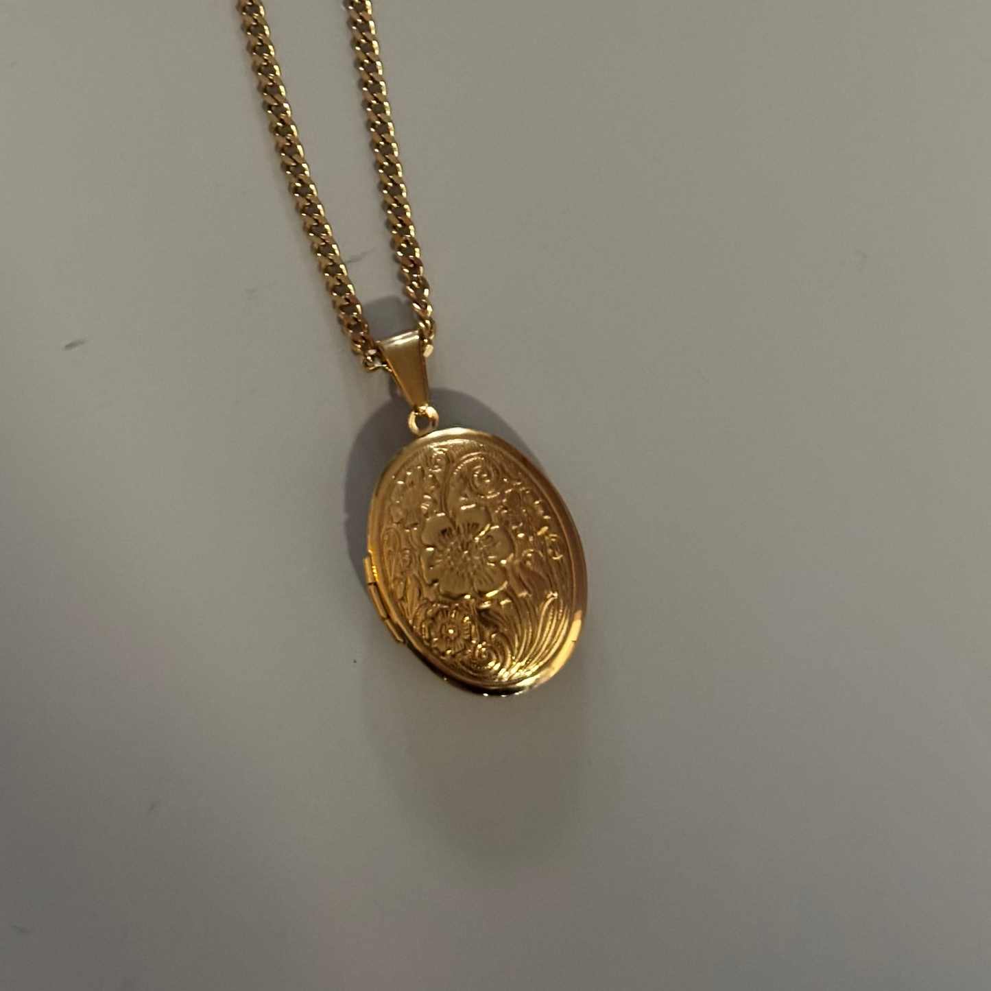 Drie medaillons: rond, ovaal en shell-vierkant, met ruimte voor een foto, op 14k vergulde kettingen van 45 en 60 cm.