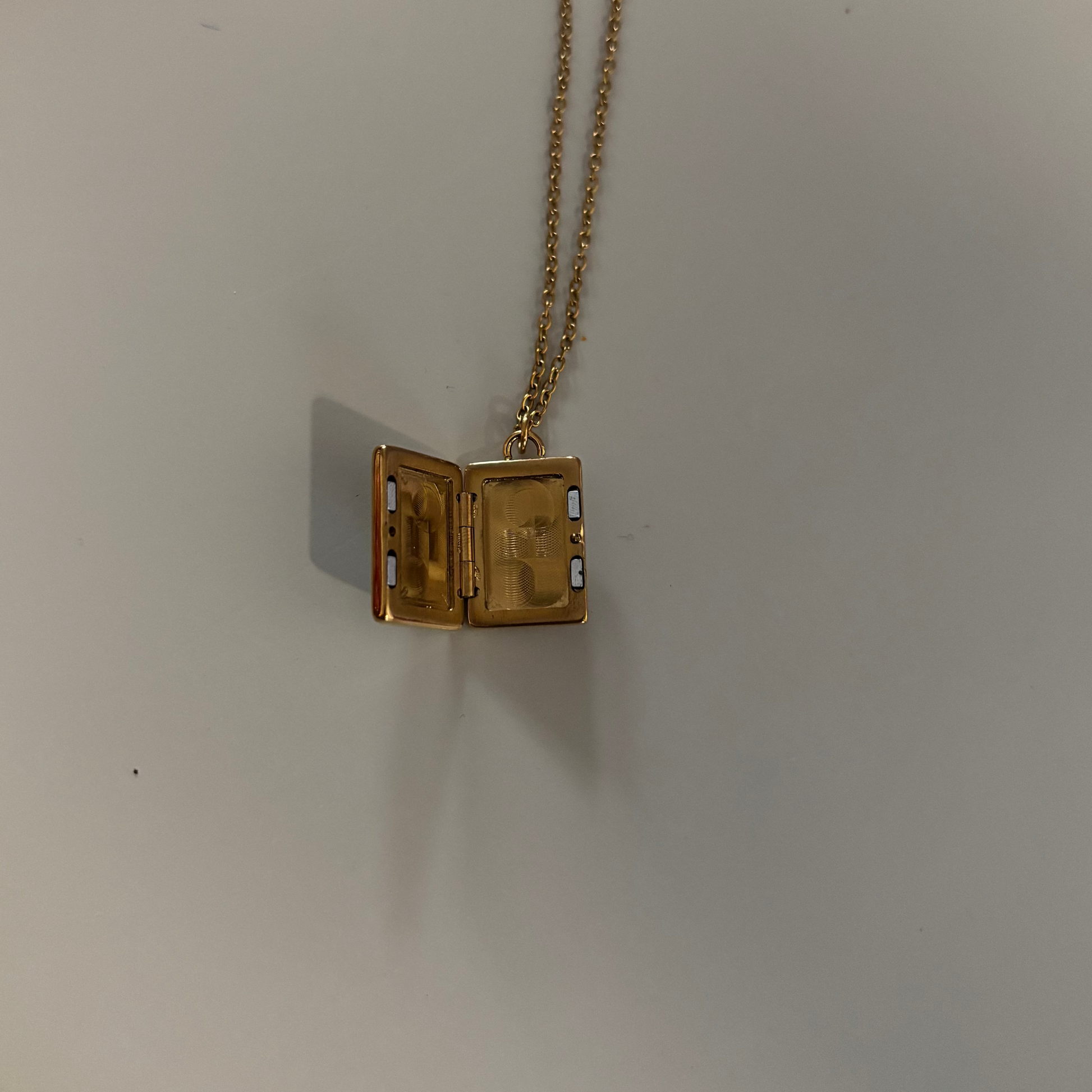 Drie medaillons: rond, ovaal en shell-vierkant, met ruimte voor een foto, op 14k vergulde kettingen van 45 en 60 cm.