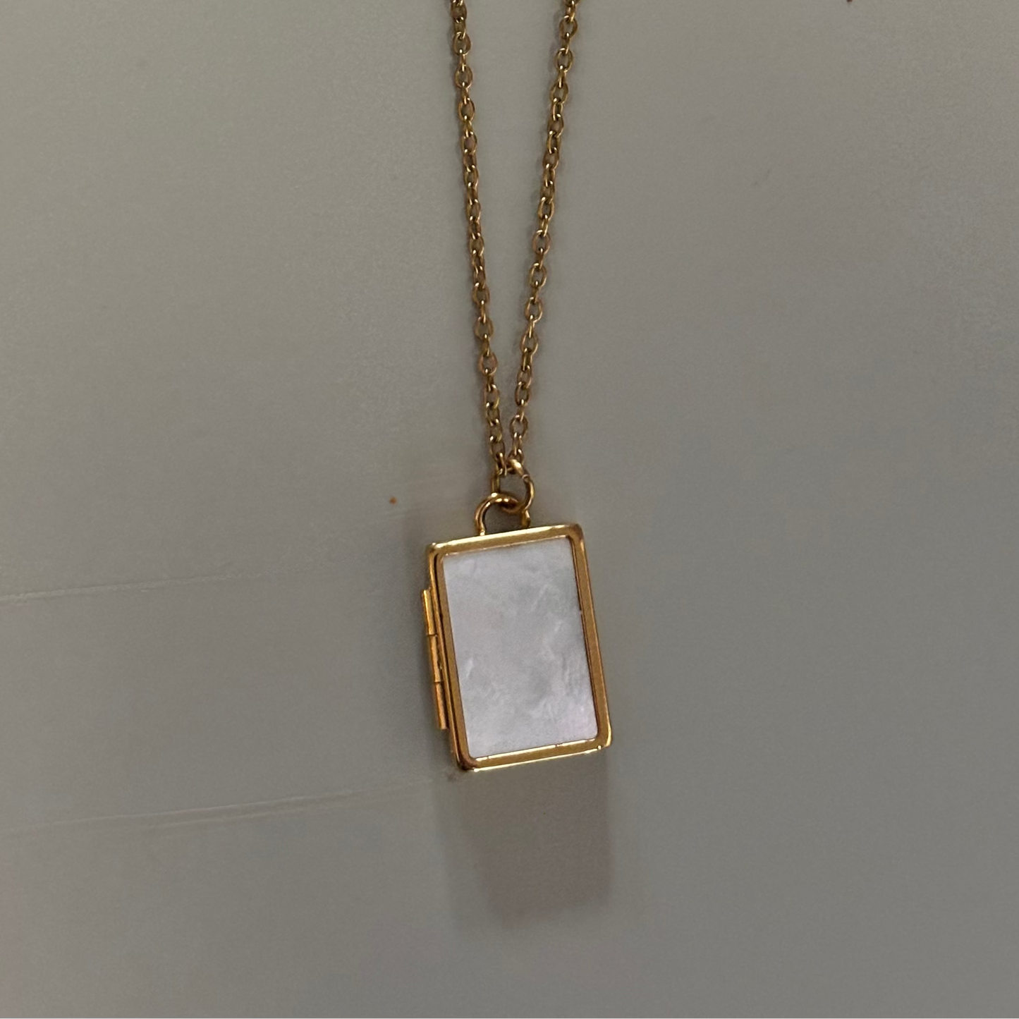 Drie medaillons: rond, ovaal en shell-vierkant, met ruimte voor een foto, op 14k vergulde kettingen van 45 en 60 cm.