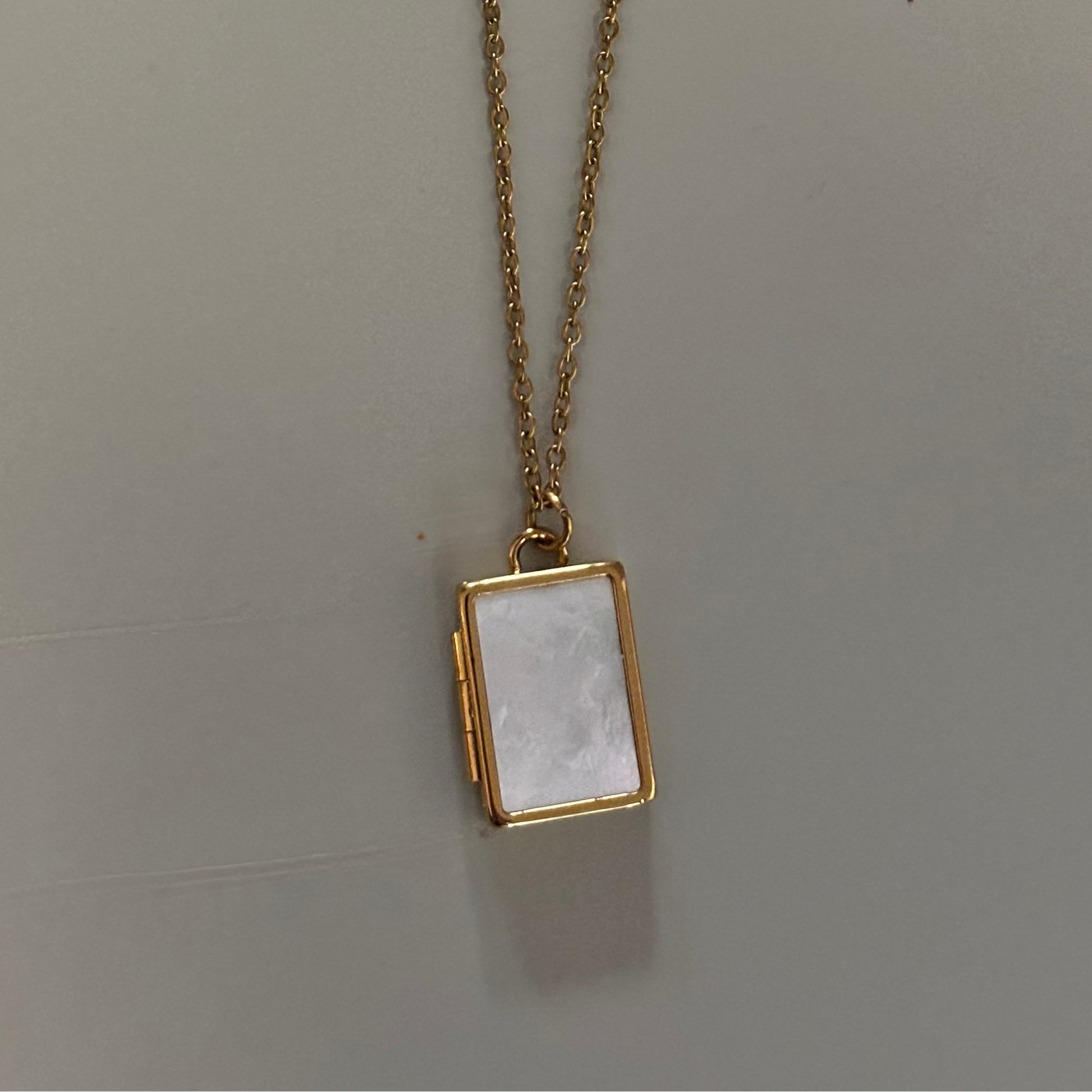 Drie medaillons: rond, ovaal en shell-vierkant, met ruimte voor een foto, op 14k vergulde kettingen van 45 en 60 cm.