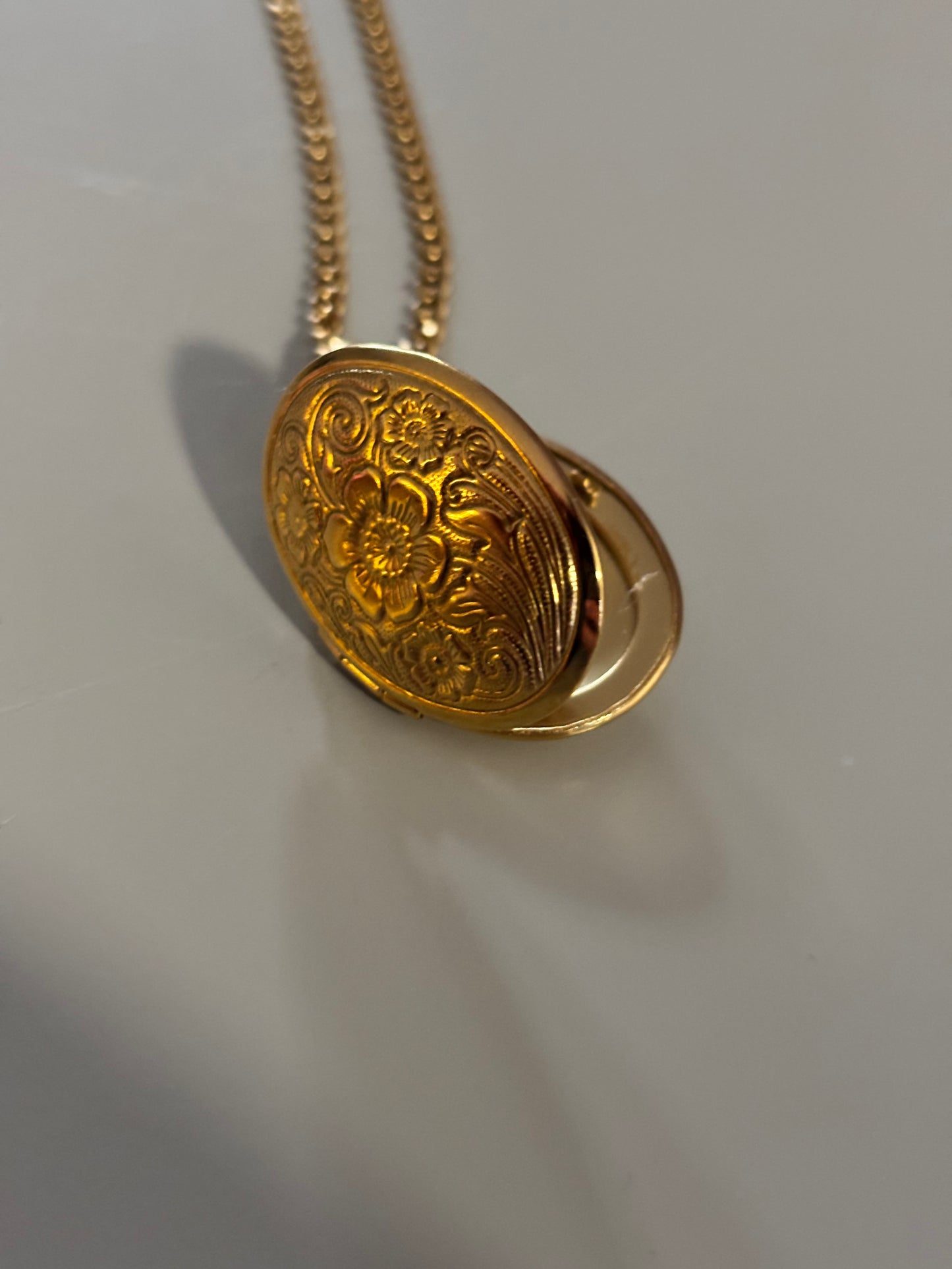 Drie medaillons: rond, ovaal en shell-vierkant, met ruimte voor een foto, op 14k vergulde kettingen van 45 en 60 cm.