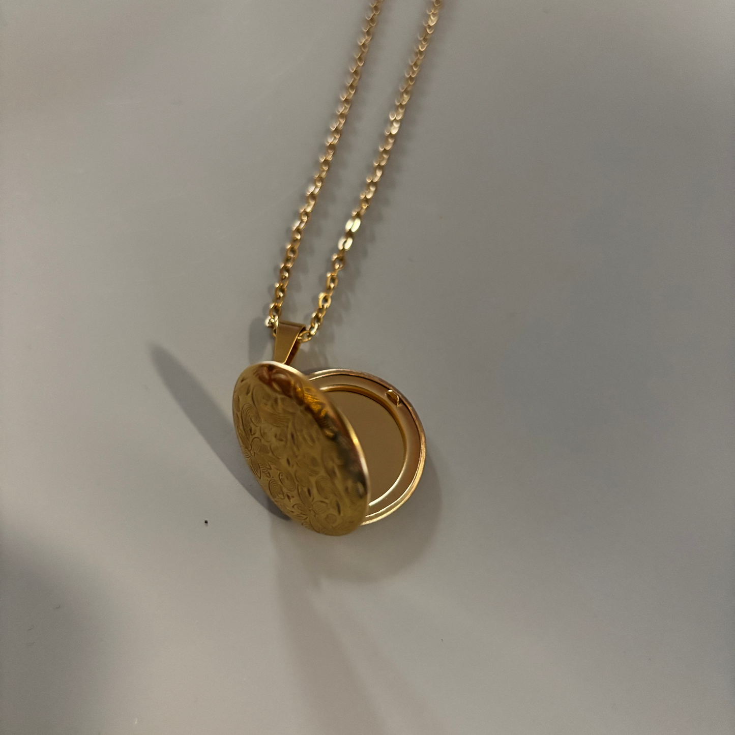 Drie medaillons: rond, ovaal en shell-vierkant, met ruimte voor een foto, op 14k vergulde kettingen van 45 en 60 cm.