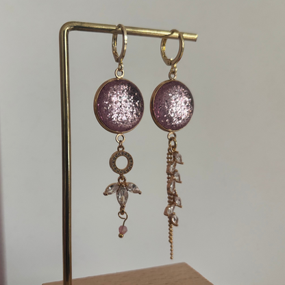 Asymmetrische 14k vergulde oorbellen 'Nina' met glinsterende roze ronde stenen en hangers van heldere kristallen op een gouden standaard.