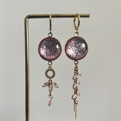 Asymmetrische 14k vergulde oorbellen 'Nina' met glinsterende roze ronde stenen en hangers van heldere kristallen op een gouden standaard.