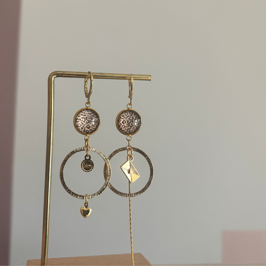 Asymmetrische 14k vergulde feestoorbellen met gehamerde bedels — één met envelopje, één met hartje. Elegant, symbolisch en sprankelend.