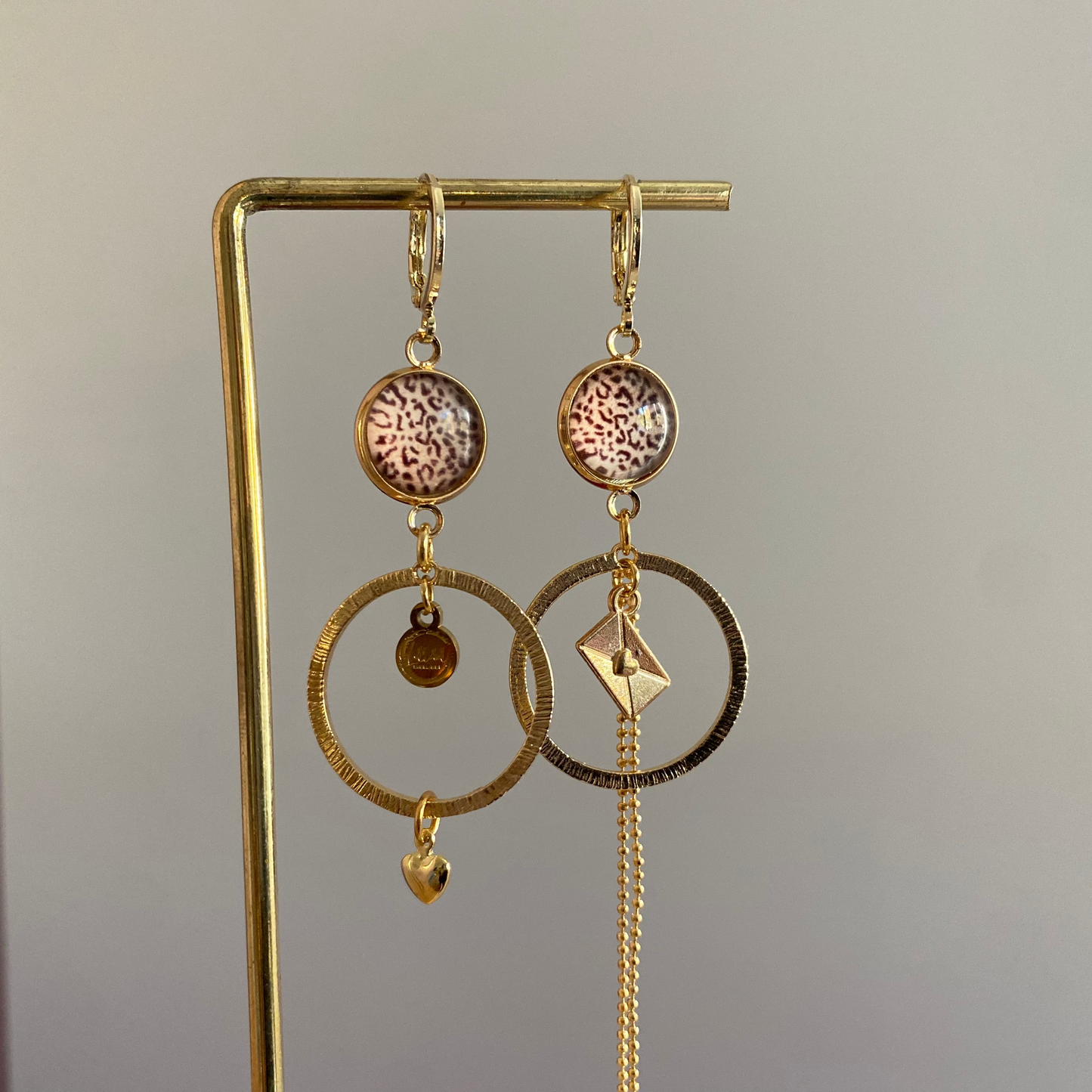 Asymmetrische 14k vergulde feestoorbellen met gehamerde bedels — één met envelopje, één met hartje. Elegant, symbolisch en sprankelend.