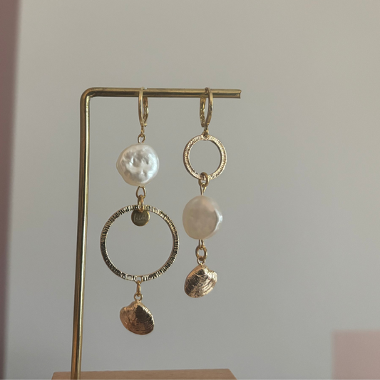 Asymmetrische oorbellen met gehamerde ringen, parel en schelp, circa 6 cm lang.