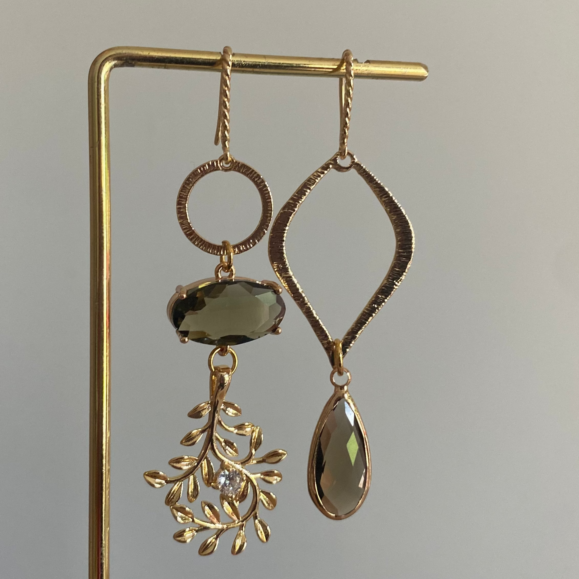 Asymmetrisch oorbelpaar met taupe glasbedel, 14k vergulde takvormige bedel en gehamerde druppel