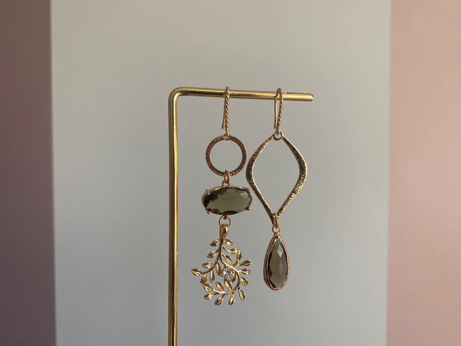 Asymmetrisch oorbelpaar met taupe glasbedel, 14k vergulde takvormige bedel en gehamerde druppel