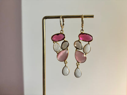 Speelse 14k vergulde oorbellen met een trosje edelstenen in framboosrood, zachtroze, rookkwarts en witte maansteen, licht van gewicht en ca. 5 cm middel­lange lengte.