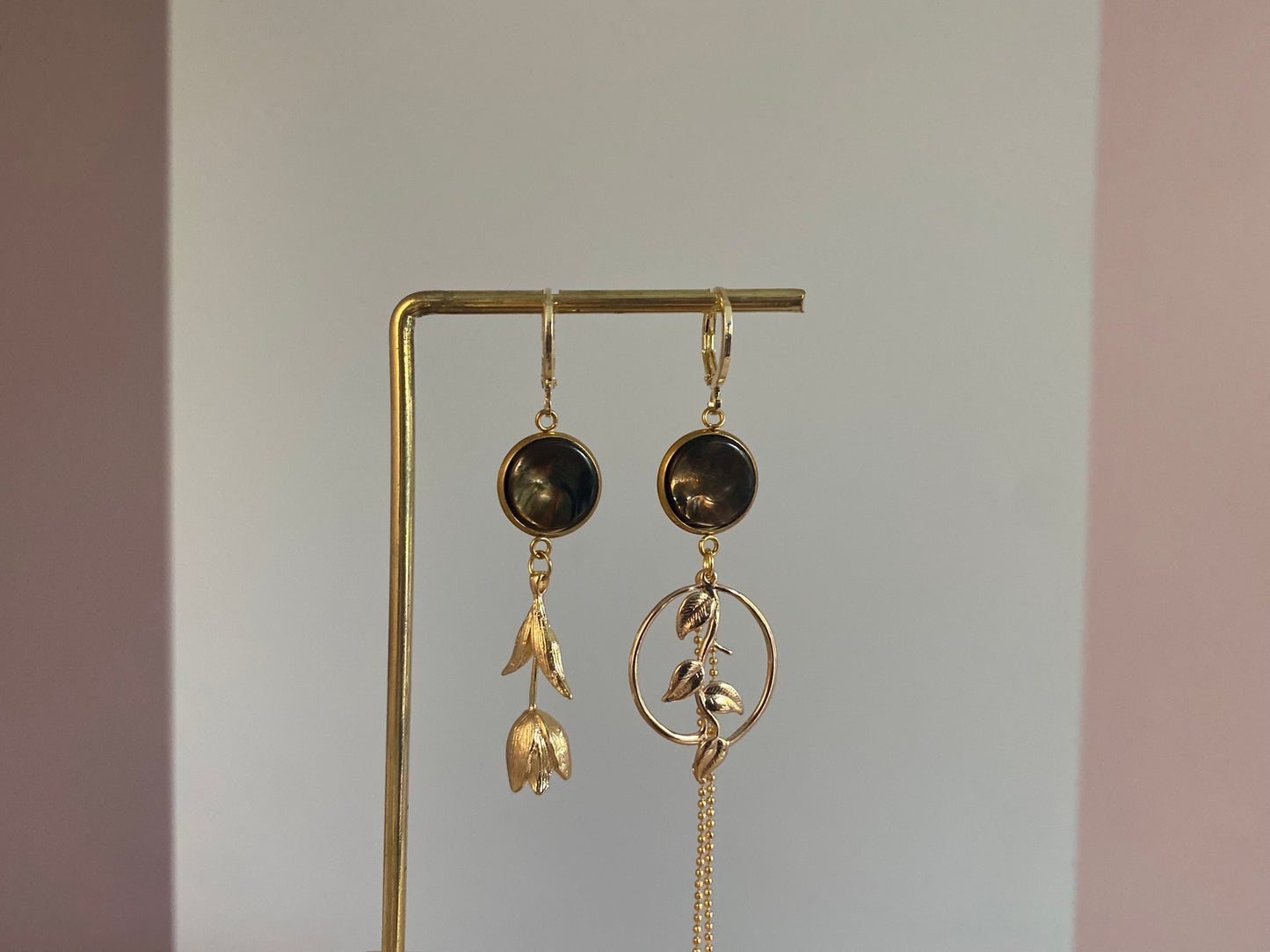 Asymmetrische 14k vergulde oorbellen met donkerbruine cabochons, tulp aan de ene kant en plantenhanger met kwastje aan de andere kant.