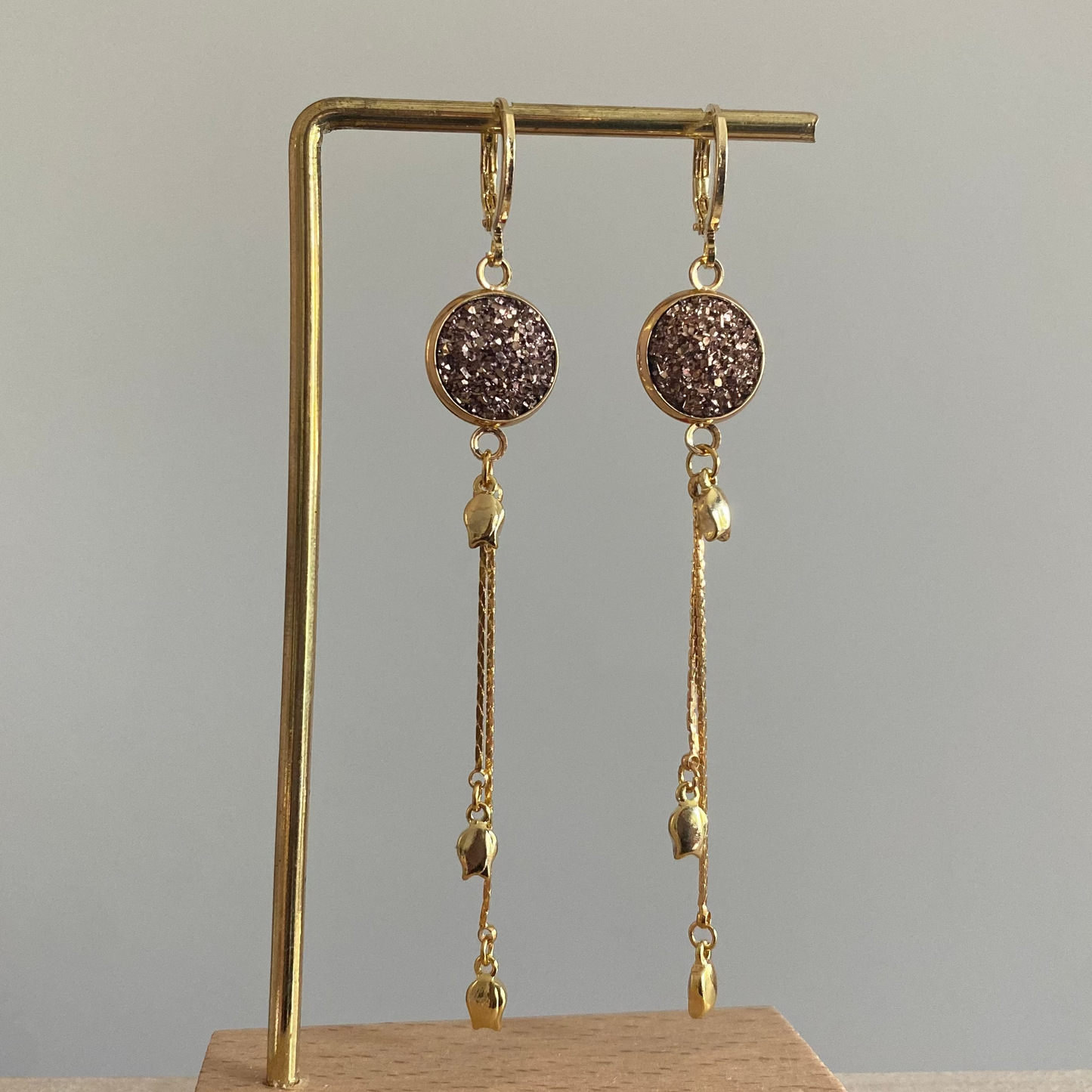 Symmetrisch paar 14k vergulde oorbellen met rosékleurige glitter cabochon en een kwastje met drie mini tulpjes.