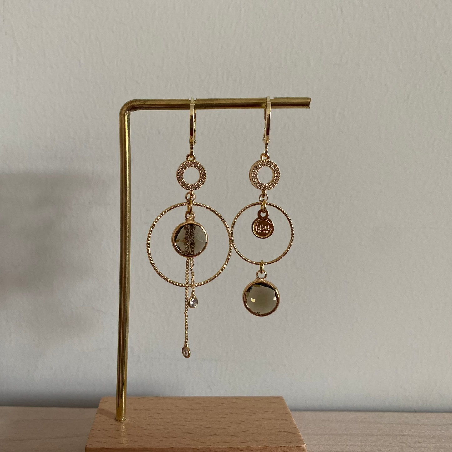 Een productfoto van het ongelijke paar Lellebel Oorbellen "Sandra", met zirkonia hangers en taupe kleurige glasbedels.