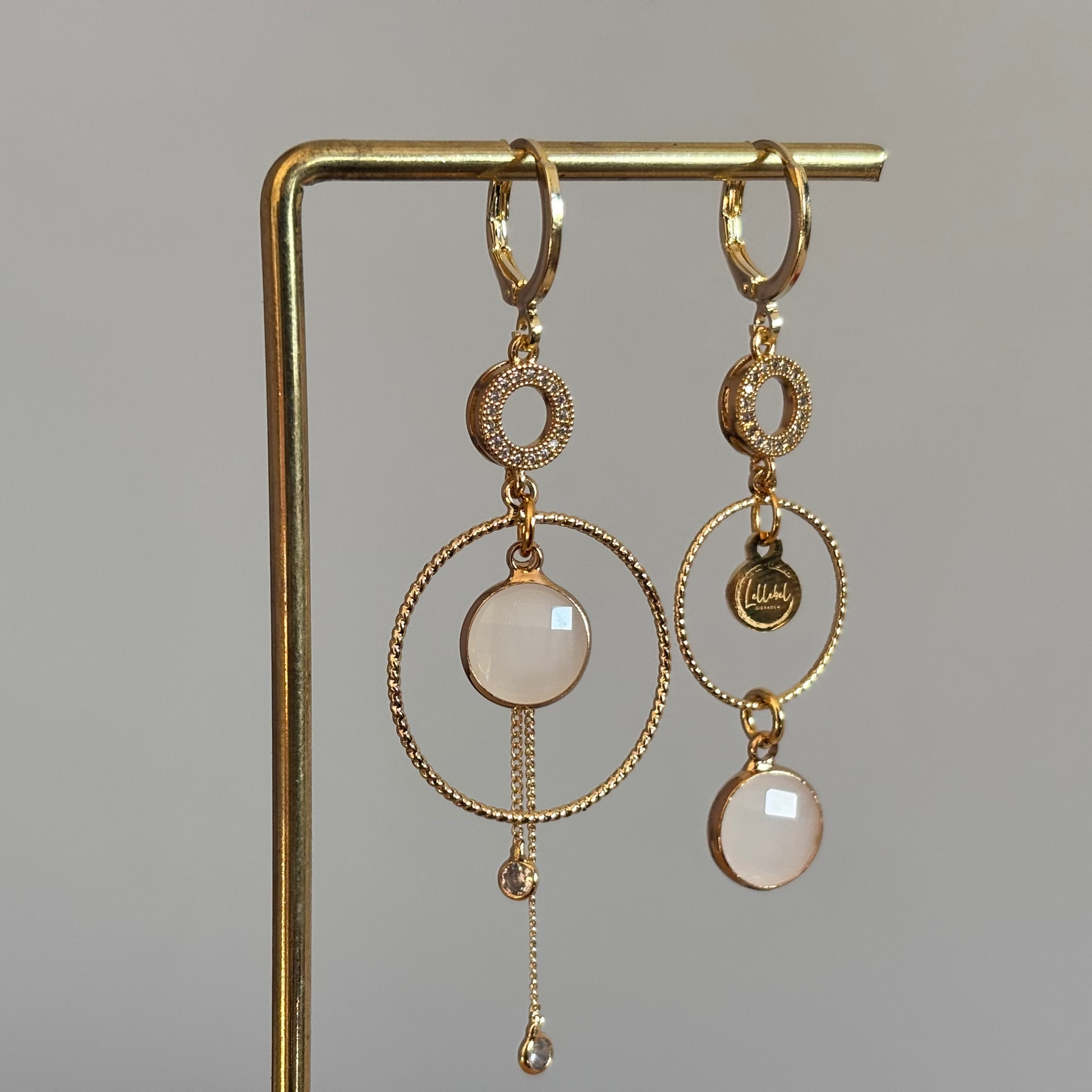 Een productfoto van het ongelijke paar Lellebel Oorbellen "Sandra", met zirkonia hangers en witte glasbedels.