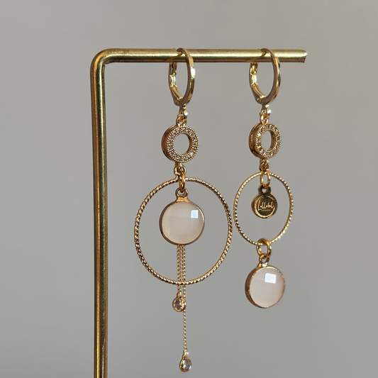 Een productfoto van het ongelijke paar Lellebel Oorbellen "Sandra", met zirkonia hangers en witte glasbedels.