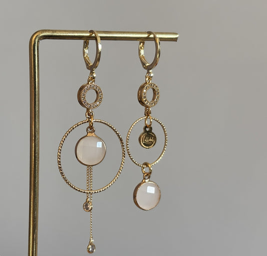 Een productfoto van het ongelijke paar Lellebel Oorbellen "Sandra", met zirkonia hangers en witte glasbedels.