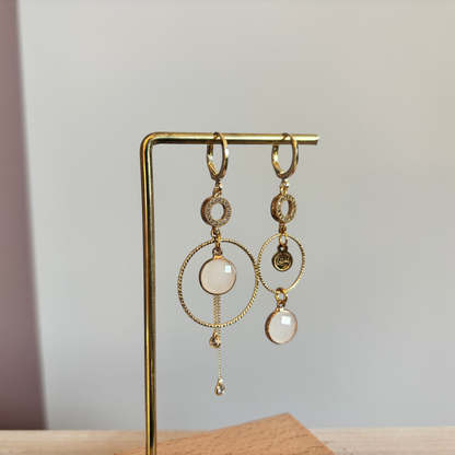 Een productfoto van het ongelijke paar Lellebel Oorbellen "Sandra", met zirkonia hangers en witte glasbedels.