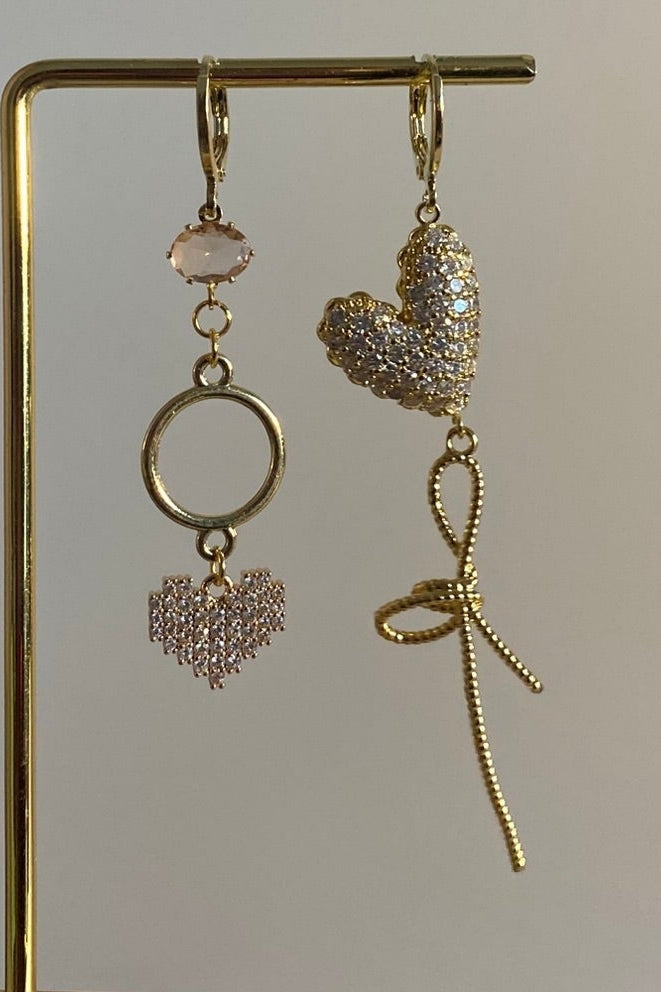 Asymmetrisch handgemaakt paar met 14k vergulde hangers en zirkonia hart bedels en een mini zachtroze glasbedel.