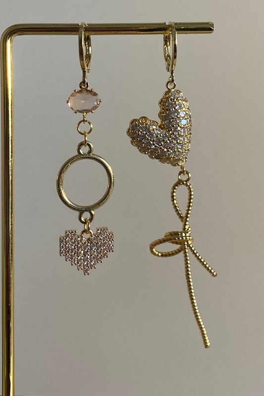 Asymmetrisch handgemaakt paar met 14k vergulde hangers en zirkonia hart bedels en een mini zachtroze glasbedel.