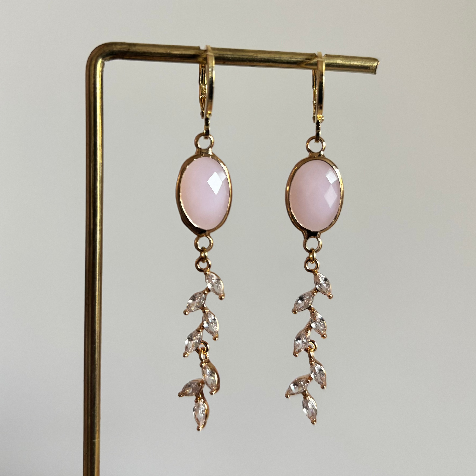 Soof oorbellen van 14k goud verguld met een ovale lichtroze steen en een hanger van zirkonia steentjes in de vorm van een takje.