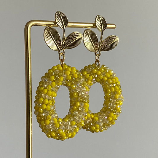 Handgemaakte bold statement oorbel met gele kralenhanger en een 14K vergulde gouden bladsteker.