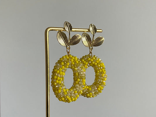 Handgemaakte bold statement oorbel met gele kralenhanger en een 14K vergulde gouden bladsteker.