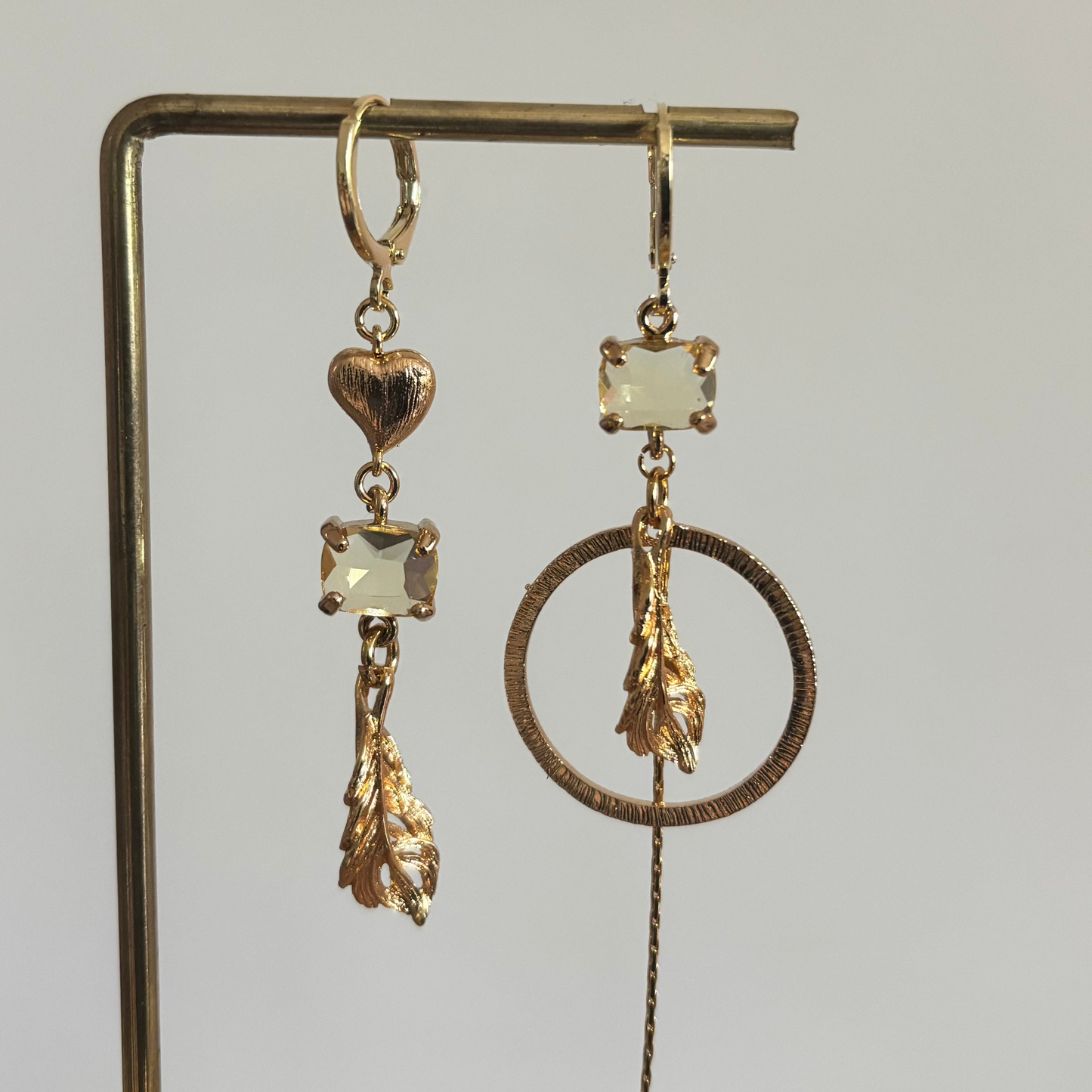 Veertje mismatch oorbellen goud met veer, hartje, glasbedel en kwastje, asymmetrisch design