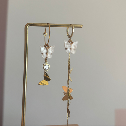 Asymmetrisch paar met 14K vergulde vlinderstreng, Shell vlinders en een mini glazen hartjesbedel, aan een 14K gouden oorringetje