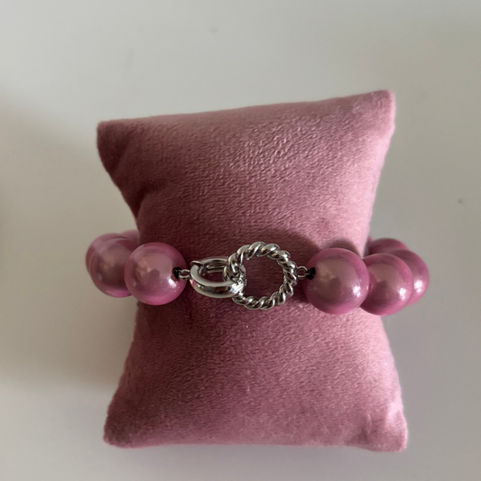 Een kralenarmband genaamd Armband 3D Zilver met ronde, parelmoerroze kralen. De armband heeft in het midden een opvallende zilverkleurige sluiting bestaande uit een gladde ring en een gedraaid zilverkleurig ringetje.