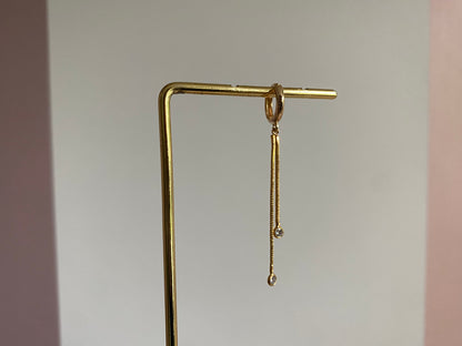 Handgemaakte 14K vergulde oorbel met daaraan een 14K vergulden gouden strengetje met zirkonia bedels.