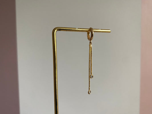 Handgemaakte 14K vergulde oorbel met daaraan een 14K vergulden gouden strengetje met zirkonia bedels.
