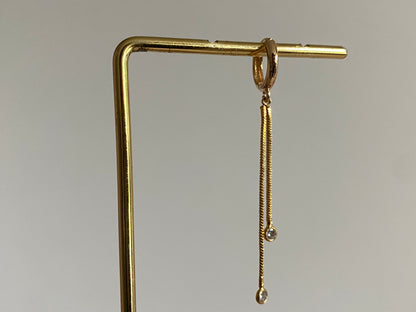 Handgemaakte 14K vergulde oorbel met daaraan een 14K vergulden gouden strengetje met zirkonia bedels.