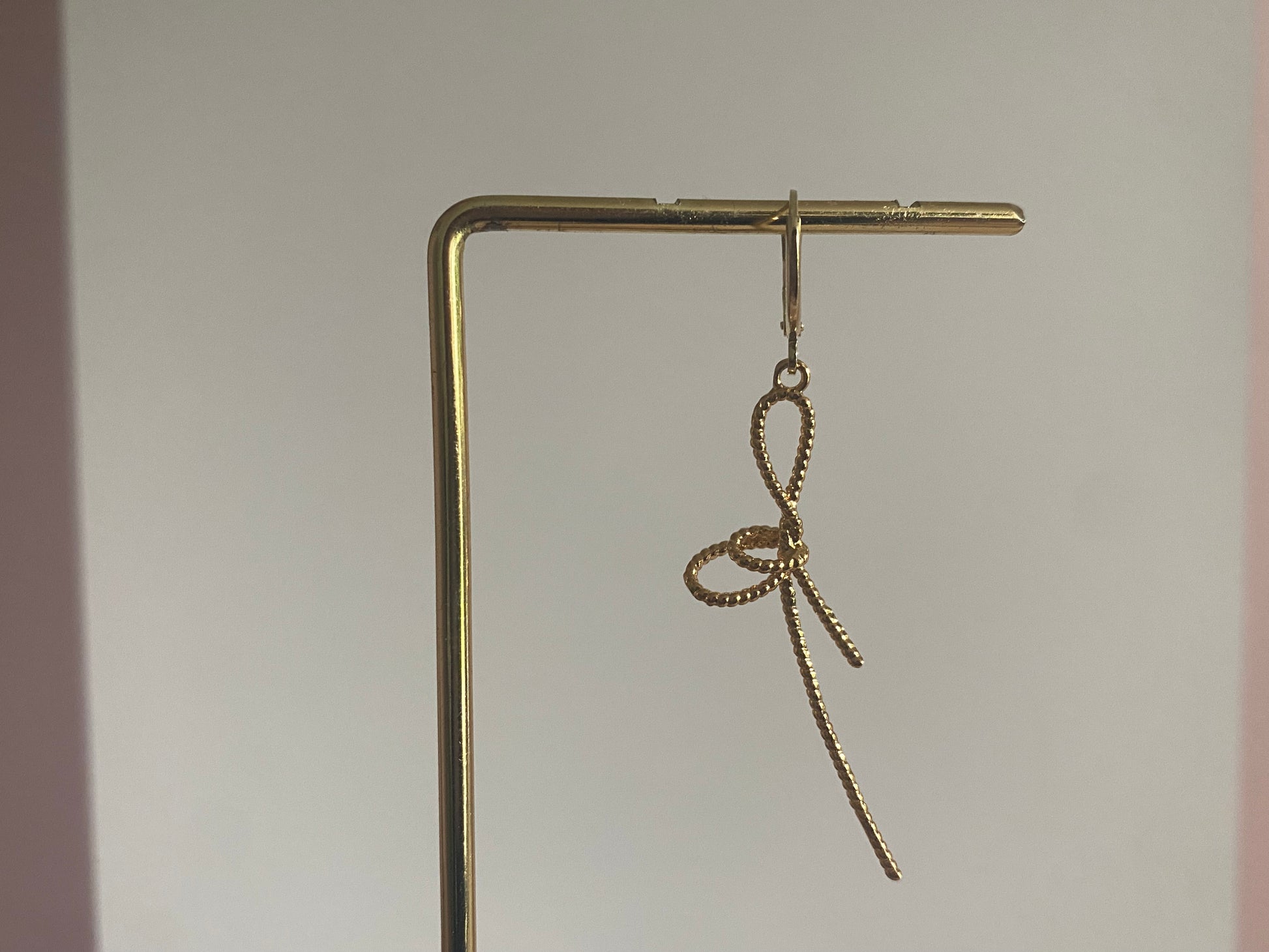 Handgemaakte earparty oorbel met een 14K verguld oorringetje en een stainless steel opengewerkte strik