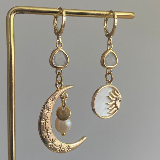 Asymmetrische oorbellen met een 14K gouden vergulde maan, glasbedel en een parelmoerhanger met daarin een 14K vergulde zon en zirkonia.