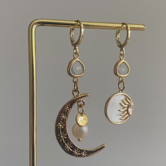 Filmpje van Asymmetrische oorbellen met een 14K gouden vergulde maan, glasbedel en een parelmoerhanger met daarin een 14K vergulde zon en zirkonia.