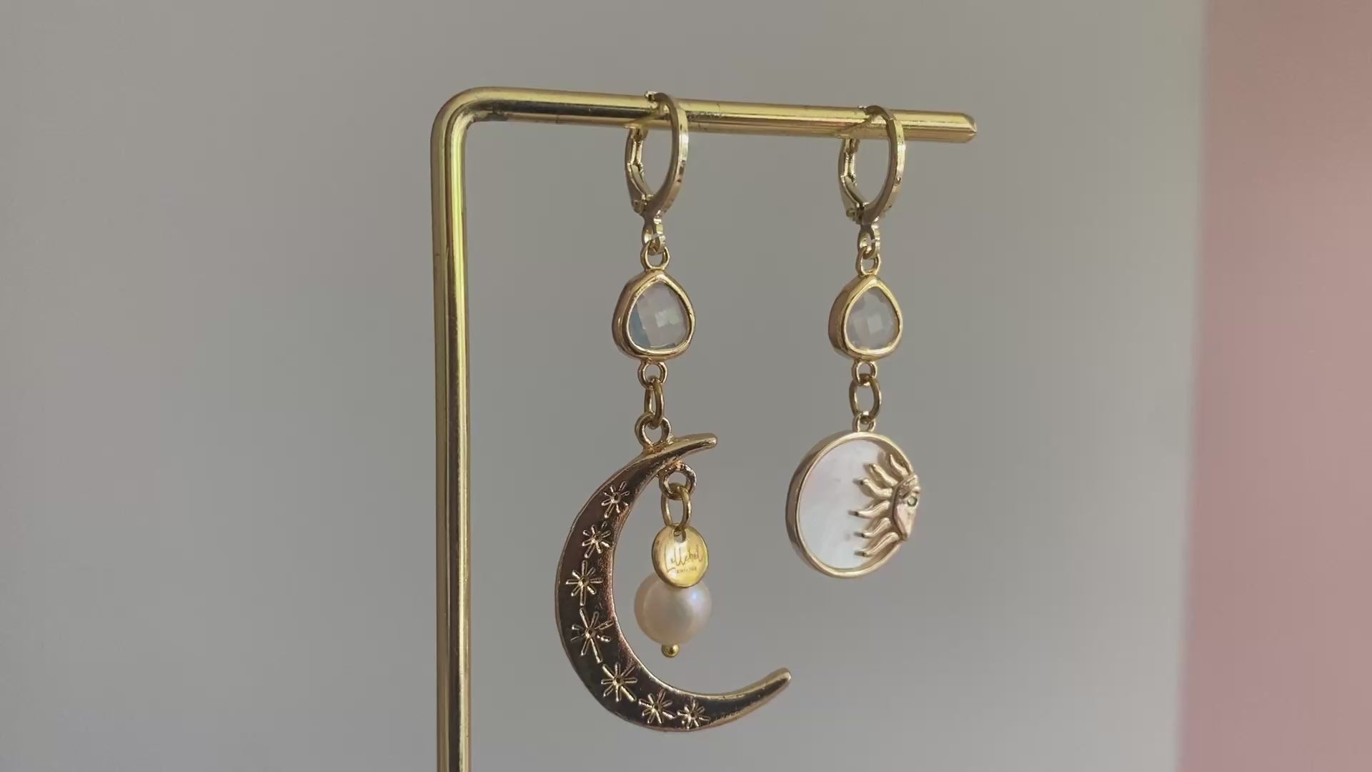 Filmpje van Asymmetrische oorbellen met een 14K gouden vergulde maan, glasbedel en een parelmoerhanger met daarin een 14K vergulde zon en zirkonia.