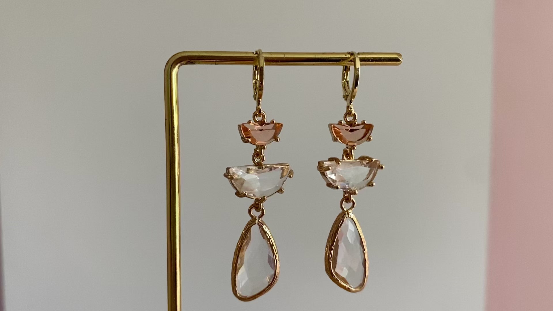 filmpje van 14K vergulde ringetjes met perzikkleurige halve maan glasbedel, een transparante halve maan glasbedel en een asymmetrische transparante langwerpige glasbedel.