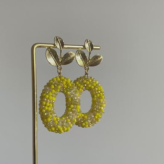 Filmpje van Handgemaakte bold statement oorbel met gele kralenhanger en een 14K vergulde gouden bladsteker.