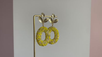 Filmpje van Handgemaakte bold statement oorbel met gele kralenhanger en een 14K vergulde gouden bladsteker.