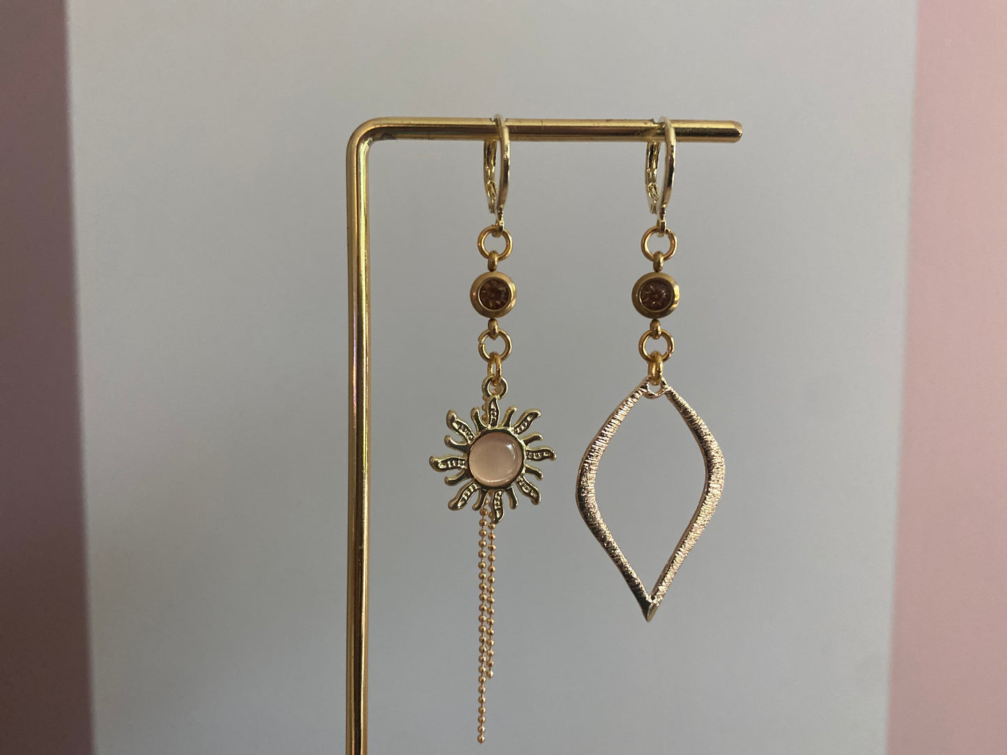 Asymmetrische oorbellen van 14K verguld goud met een zon van een cateye steen en een gehamerde 14K vergulde druppelvormige hanger en dieporanje zirkonia bedeltjes.
