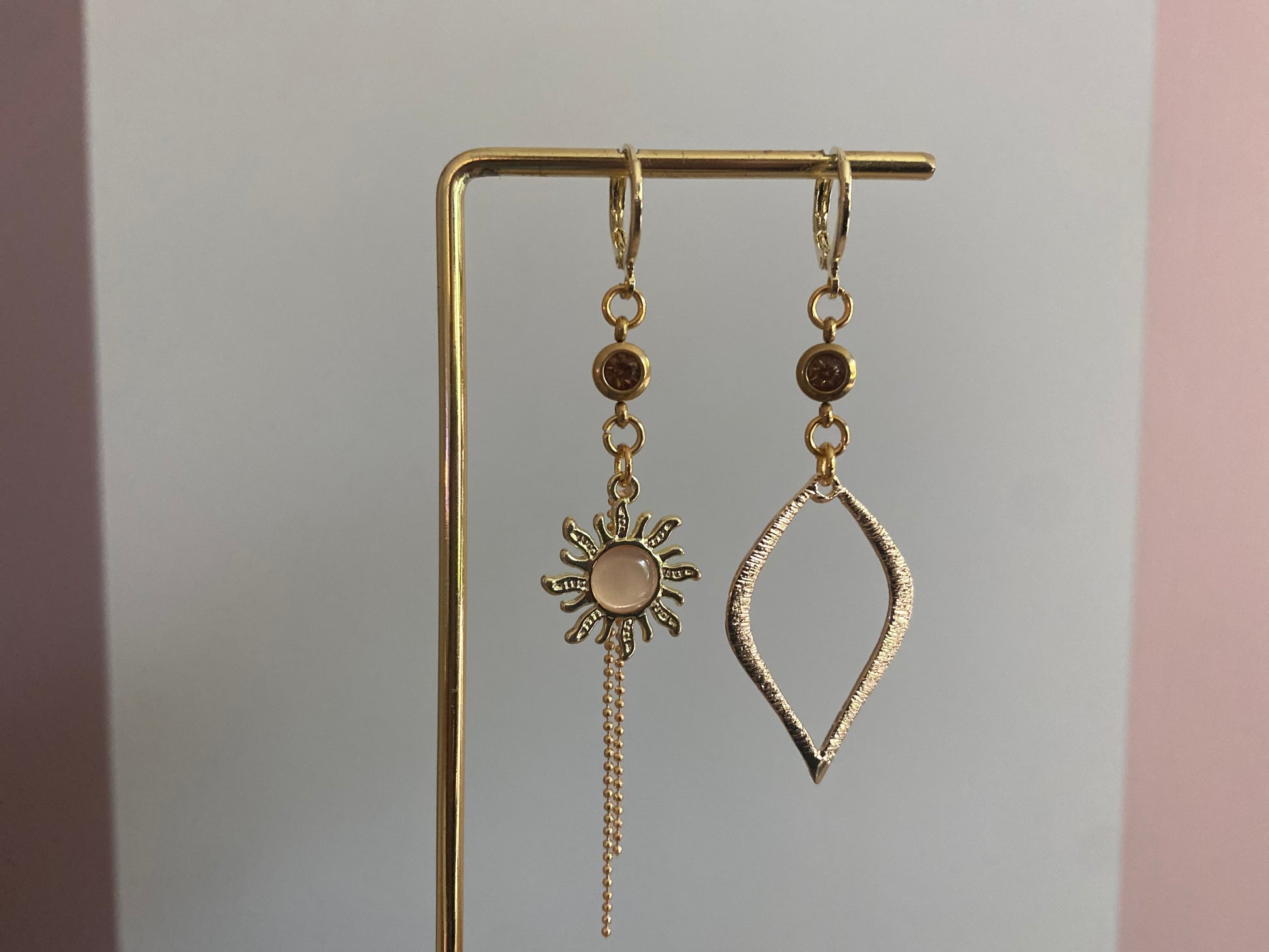 Asymmetrische oorbellen van 14K verguld goud met een zon van een cateye steen en een gehamerde 14K vergulde druppelvormige hanger en dieporanje zirkonia bedeltjes.