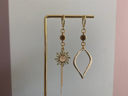 Asymmetrische oorbellen van 14K verguld goud met een zon van een cateye steen en een gehamerde 14K vergulde druppelvormige hanger en dieporanje zirkonia bedeltjes.