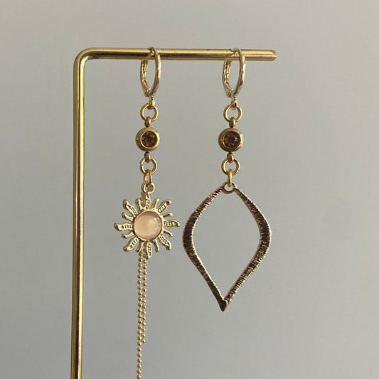 Asymmetrische oorbellen van 14K verguld goud met een zon van een cateye steen en een gehamerde 14K vergulde druppelvormige hanger en dieporanje zirkonia bedeltjes.